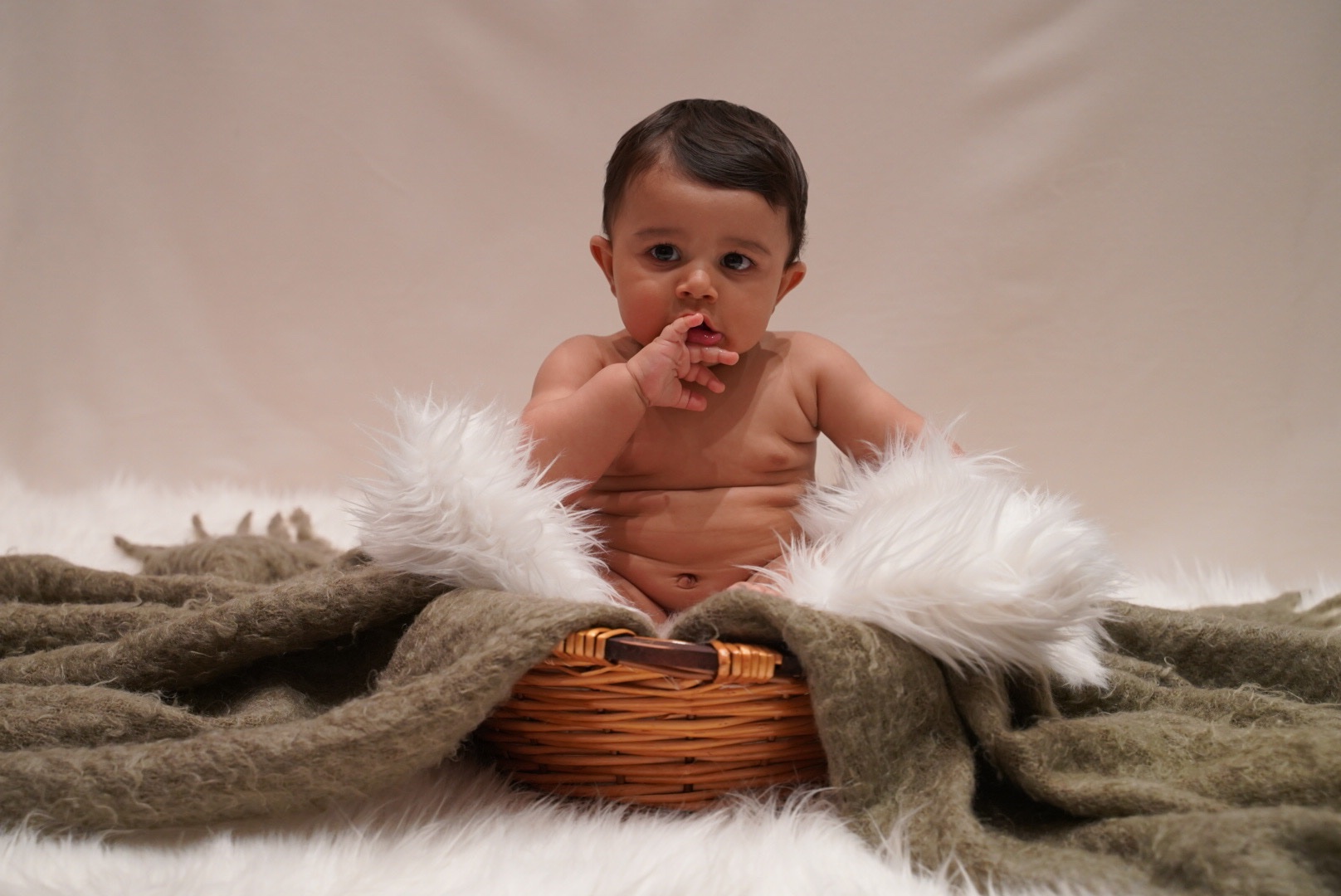 Baby photographed with soft blankets and a basket in the Clickography studio