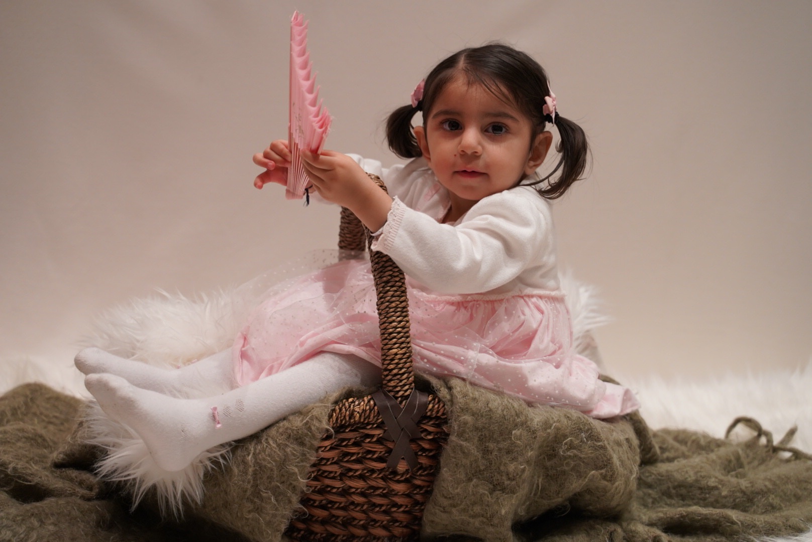 Young child photographed with a basket and playful studio prop