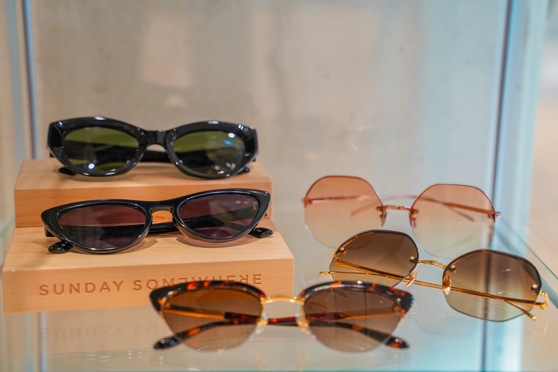 Collection of sunglasses displayed on branded wooden presentation blocks