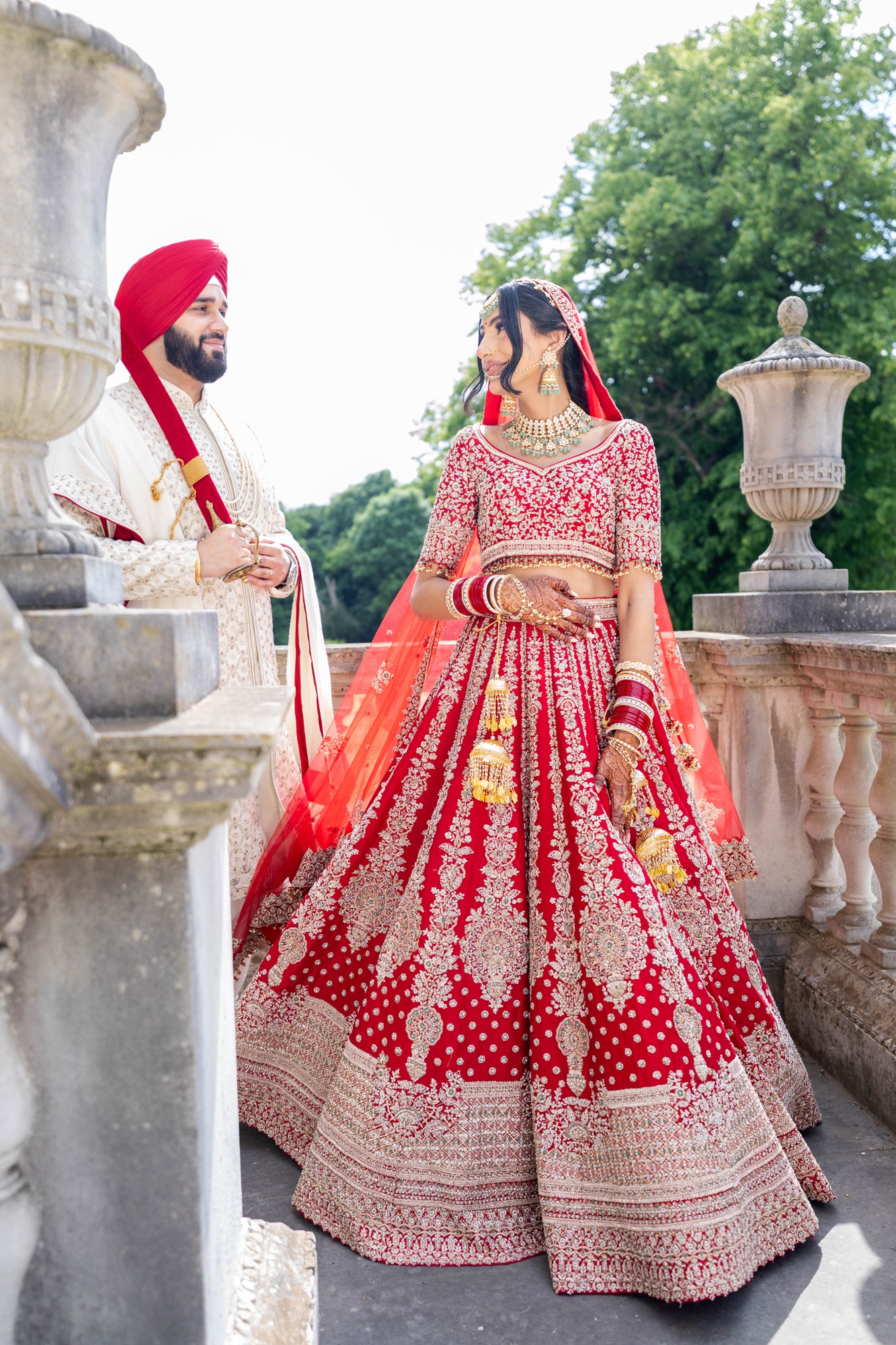 Sikh bride and groom sharing a quiet look on a stone terrace