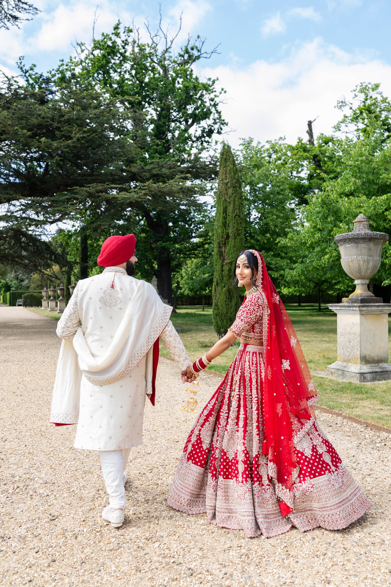 Newly married couple walking hand in hand through the venue gardens
