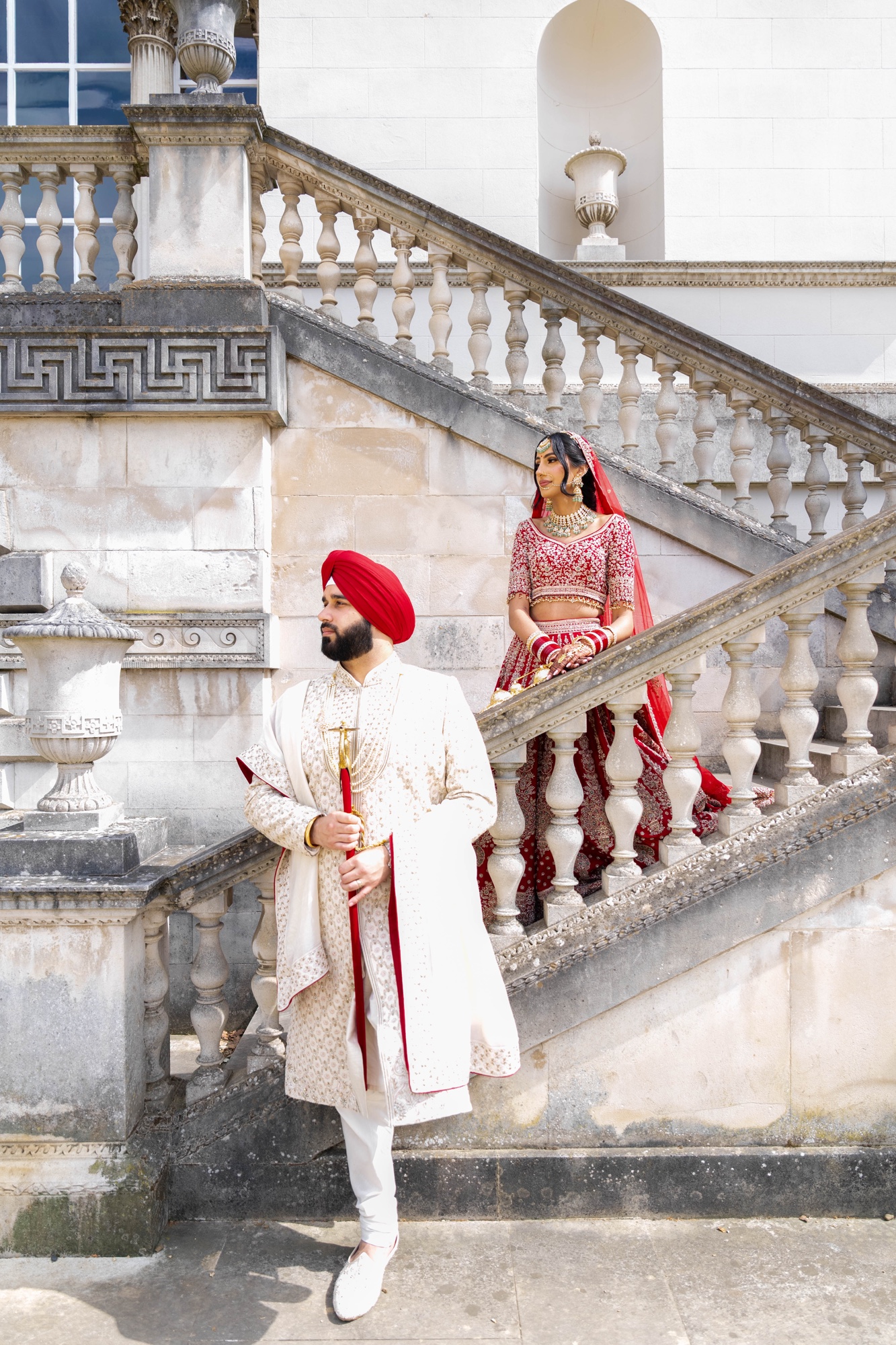 Bride and groom posed on different levels of an ornate stone staircase