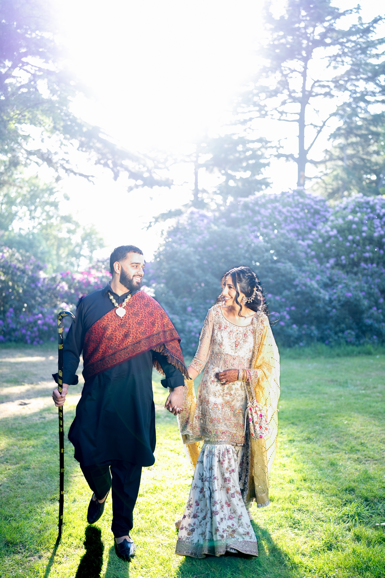 Wedding couple walking together through a sunlit flowering garden