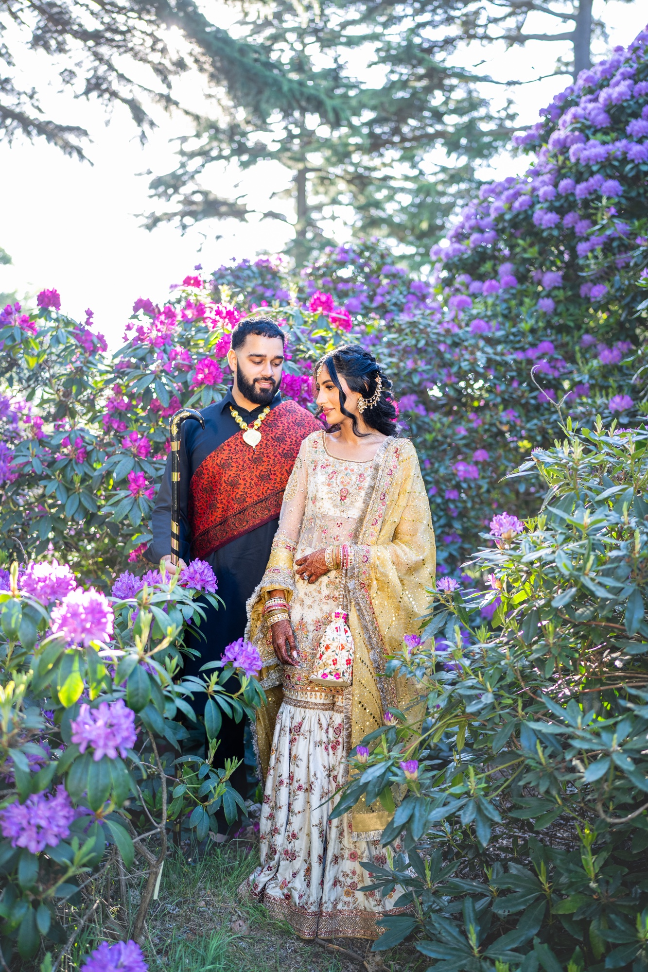 Wedding couple standing closely among vivid purple flowers
